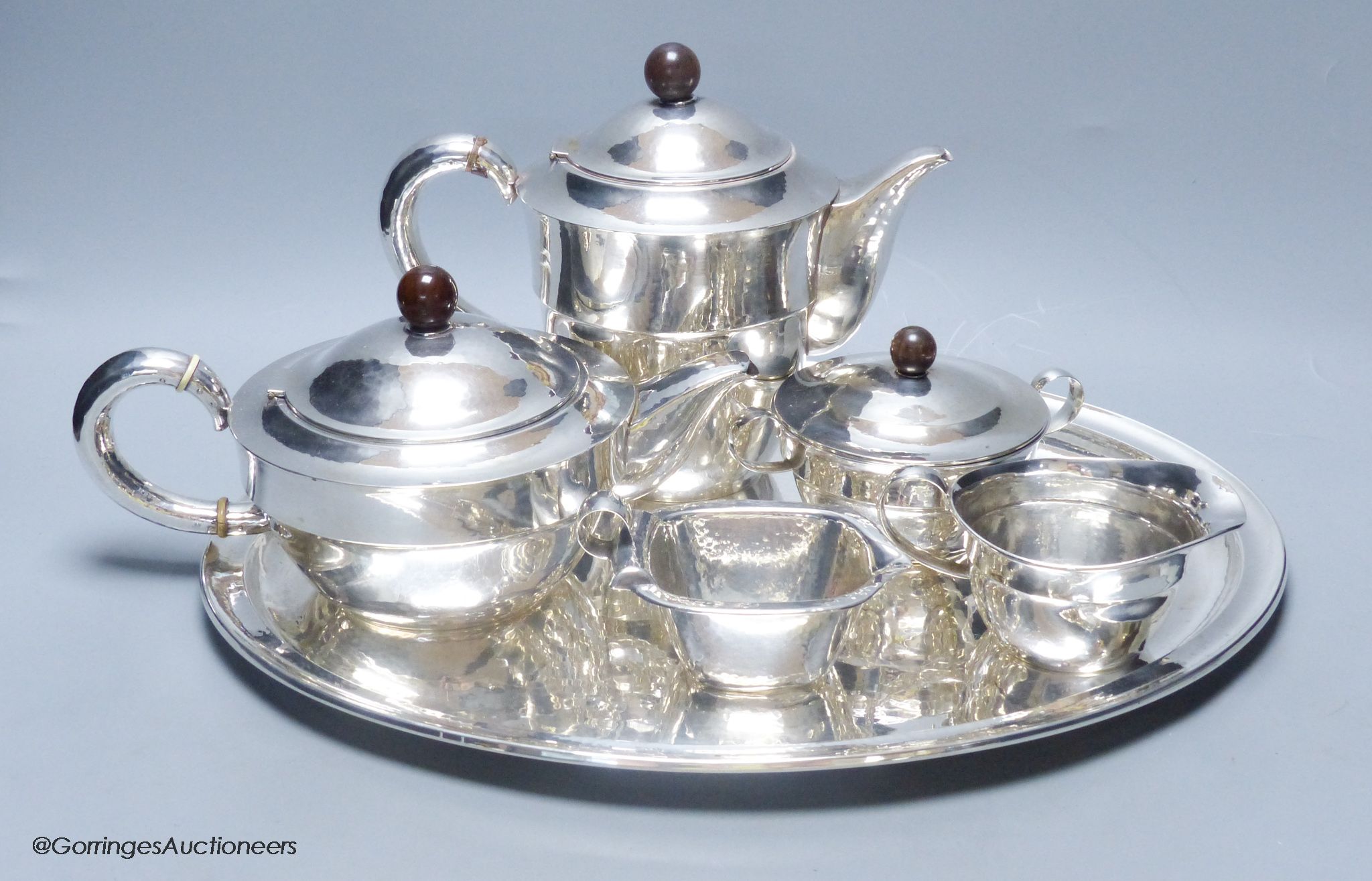 An early 20th century German planished 830s white metal six piece tea and coffee service comprising oval tray, teapot, coffee pot, creamer and milk jug, by M.H. Wilkens & Sohne